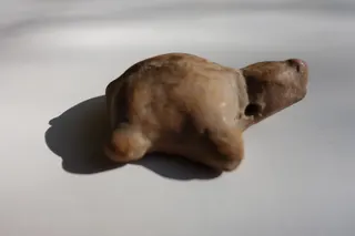 Amulett, Ton, durchbohrt, damit es aufgefädelt um den Hals getragen werden konnte, aus Bamiyan (heute Afghanistan), baktrisch, zweites Jahrtausend vor Chr., Größe 4,5 cm. Das Objekt stammt aus der ehemaligen Sammlung von Prof. Rademacher, vermittelt über Roswitha Eberwein (international renomierte "Galerie für Antike Kunst", Göttingen), die für Echtheit und Provenienz garantiert.