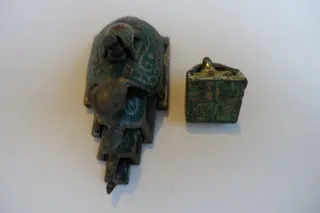 Zwei Bronzen, links: teilbemalt, mit 5 plastischen Schildkröten (ausziehbar), die alle im Boden ein unterschiedliches Siegel tragen, mit Grundflächen von ca. 0,7 x 0,9 cm bis 3,8 x 3,8 cm; rechts: goldbronziert, zwei ineinander gesteckte Schildkröten, im Boden jeweils ein Siegel, Grundfläche 2,3 x 2,3 cm und 1,7 x 1,7 cm.