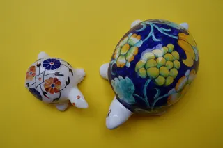 Zwei italienische Objekte. Links: Onyx mit kunstvoll gearbeiteten Steinintarsien, Größe 9,5 cm. Rechts: Keramik aus Florenz, handbemalt, sign. RR, Größe 16 cm.