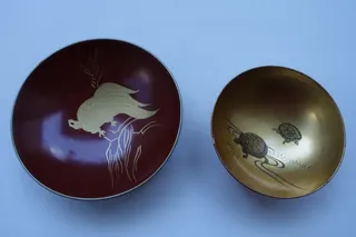 Traditionelle Lack-Schälchen. Links mit Minogame, im Boden sign., Durchmesser 8,5 cm. Rechts zwei Schildkröten in angedeuteter Landschaft, Durchmesser 6,5 cm.