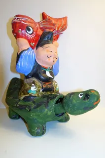 Ebisu, einer der sieben japanischen Glücksgötter, dargestellt mit den Symbolen Schildkröte (mit Wackelkopf) und Meerbrasse (Tai), aus Pappmaché, handbemalt, ca. 27 cm hoch. Das Objekt stammt aus der Collection Craft and Folk Art, Los Angeles.