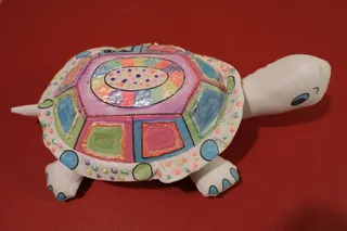 Vorgefertigte Stoffschildkröte, der Unterbau ist mit Zahlen und Buchstaben versehen, handbemalt und mit Wachstropfen betupft (Alter 11 Jahre), Größe 27 cm.