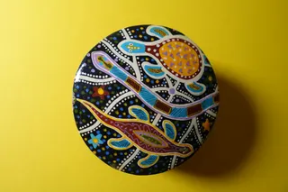 Döschen, schwarz lackiert, Durchmesser 7,5 cm, Deckel handbemalt, mit drei für die Aboriginals (Ureinwohner in Australien) besonders wichtigen Tieren. Interessant ist die Verwandtschaft des Motives von Schildkröte und Eidechse mit der indianischen Kultur, siehe buckskinbag (Nabelschnurbeutel).