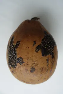 Kalebasse, naturbelassen, nur die insgesamt fünf Schildkrötenmotive sind leicht eingeritzt und gefärbt, Größe 15 cm. Solche Flaschenkürbisse wurden oft auch als Trinkgefäße benutzt.