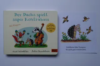 In diesem Buch mit dicken Kartonseiten (aus einer Serie mit weiteren Geschichten) finden sich fünf Illustrationen mit einer Trompete spielenden Schildkröte, von Axel Scheffler, der insbesondere durch "Der Grüffelo" bekannt geworden ist. Sechs Bilder lassen sich aufklappen (aus dem fahrbaren Kasten einer Ziege kommt dann z.B. eine Harfe heraus), Zielgruppe sind kleinere Kinder. Dieses Buch ist auch in englischer Sprache vorhanden (Titel: "Badger`s Band", die Bilder sind identisch, der Originaltext von Julia Donaldson unterscheidet sich aber spürbar von der deutschen Version).