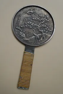 Dieser kleine Spiegel aus der Meiji-Zeit war handlicher mitzunehmen. Material und Motiv (u.a. Minogame) entsprechen jedoch weitgehend dem schon beschriebenen großen Spiegel. Durchmesser 9 cm plus Griff 8cm.