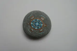 Kieselstein, handbemalt, indianisch beeinflußtes Design, sign., Größe 4,5 cm.