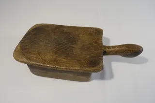 Dieser Hocker, aus einem Stück geschnitzt, gehörte einer Frau vom Stamm der Lobi und gilt als Mitgift. Der Kopf ist zugleich ein praktischer Griff. Er steht in der Regel vor der Hütte. Ist die Hausfrau länger abwesend, wird der Hocker zur Information einfach umgedreht, Größe 35 cm. Aufgrund der Patina und der Gebrauchsspuren wird das Alter auf ca. 100 Jahre geschätzt.