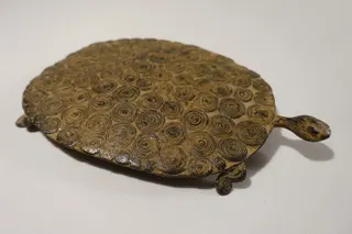 Bronze-Guss der Dogon (Mali), extrem flacher Panzer mit zahlreichen charakteristischen Kringeln und unverhältnismäßig kleinen Gliedmaßen, Länge 25 cm, Höhe 2,5 cm.
