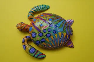 Fiberglas (Glasfaserverstärkter Kunststoff), Unikat, da farbenfroh per Hand bemalt, mit Kunstharz versiegelt und fair hergestellt, Größe 22 cm. Rückseitig sind die silbergrauen Fasern sichtbar.