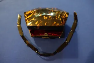 Handtasche, sechseckig, komplett aus Schildpatt, Art Deco, ca. 1920, innen mit rotem Samt gefüttert (einschließlich einer kleinen Seitentasche), tragbar an einer 9-teiligen Kette, ebenfalls aus Schildpatt, Schnappverschluß, Länge ca. 16 cm, Tiefe 6,5 cm. Die Herkunft ist nicht eindeutig, angenommen wird Frankreich.