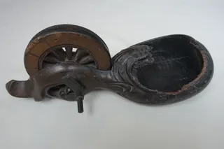 Werkzeug, aber eher das Statussymbol eines Handwerksmeisters, kunstvoll geschnitzt (s. das Glückssymbol Minogame), um 1900, Größe 28 cm. Durch das mit Ruß gefüllte Gefäß konnt mittels der Kurbel ein langer Faden eingeschwärzt werden. Der Abdruck ermöglichte dann, eine gerade Linie zu ziehen. Im Boden sind Schriftzeichen des Besitzernamesns eingraviert.