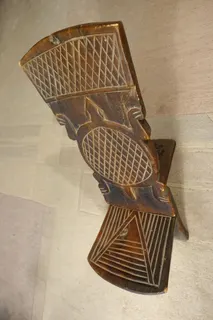 Der ältere Hocker (Sitz) eines Mannes aus der Oberschicht besteht aus zwei ineinander gesteckten Teilen und war somit gut transportierbar, Größe 73 x 56 x 28 cm. In die ungewöhnlich hohe Rückenlehne sind auf Vorder- und Rückseite unterschiedliche Schildkrötenmotive eingeschnitzt. Die Arbeit zeugt von der Kunstfertigkeit, z.B. der Bobo. Da in Mali aber ca. 20 ethnische Gruppen leben, ist das Stück nicht klar zuzuordnen.