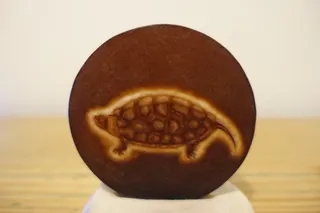 Das Motiv wurde von der befreundeten Goldschmiedin in eine transparente Glasscheibe eingraviert, Durchmesser 7 cm. Außerdem hat sie mir einige internationale Objekte beschafft.