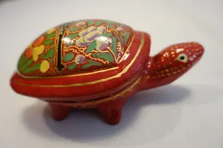 Lack-Dose aus Pappmaché, handbemalt (in der aus Kaschmir / Indien mehrfach vertretenen Technik), hier jedoch aus Pushkar (im nordindischen Bundesstaat Rajasthan), Größe ca. 15 cm.
